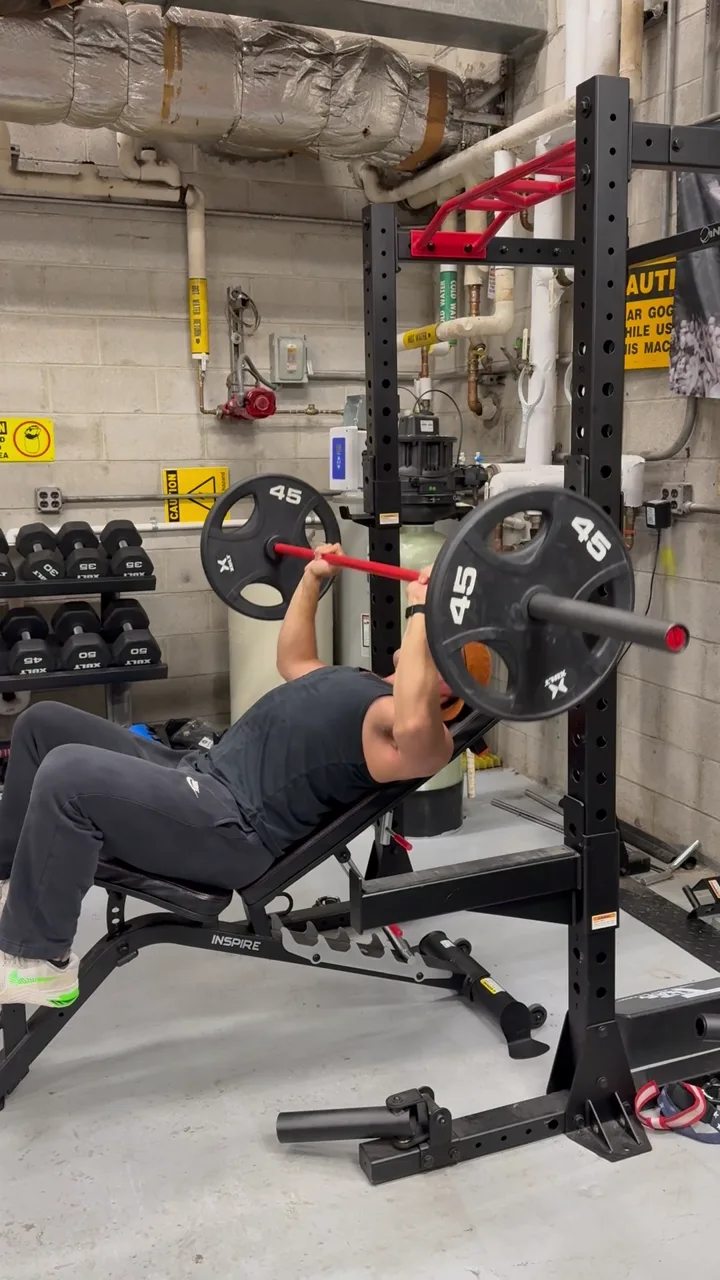 Incline barbell bench press in a squat rack during an on-site corporate session