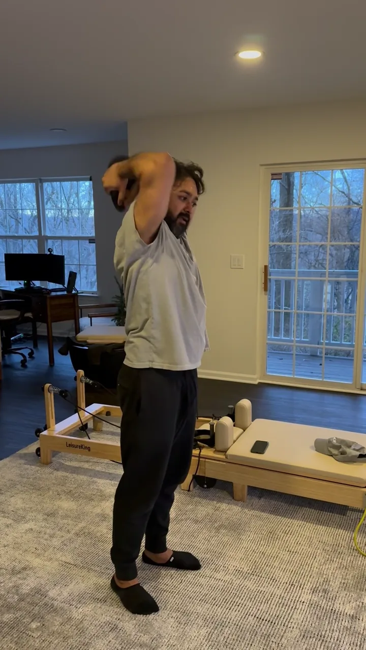 Overhead kettlebell triceps extension in a living room during an in-home session