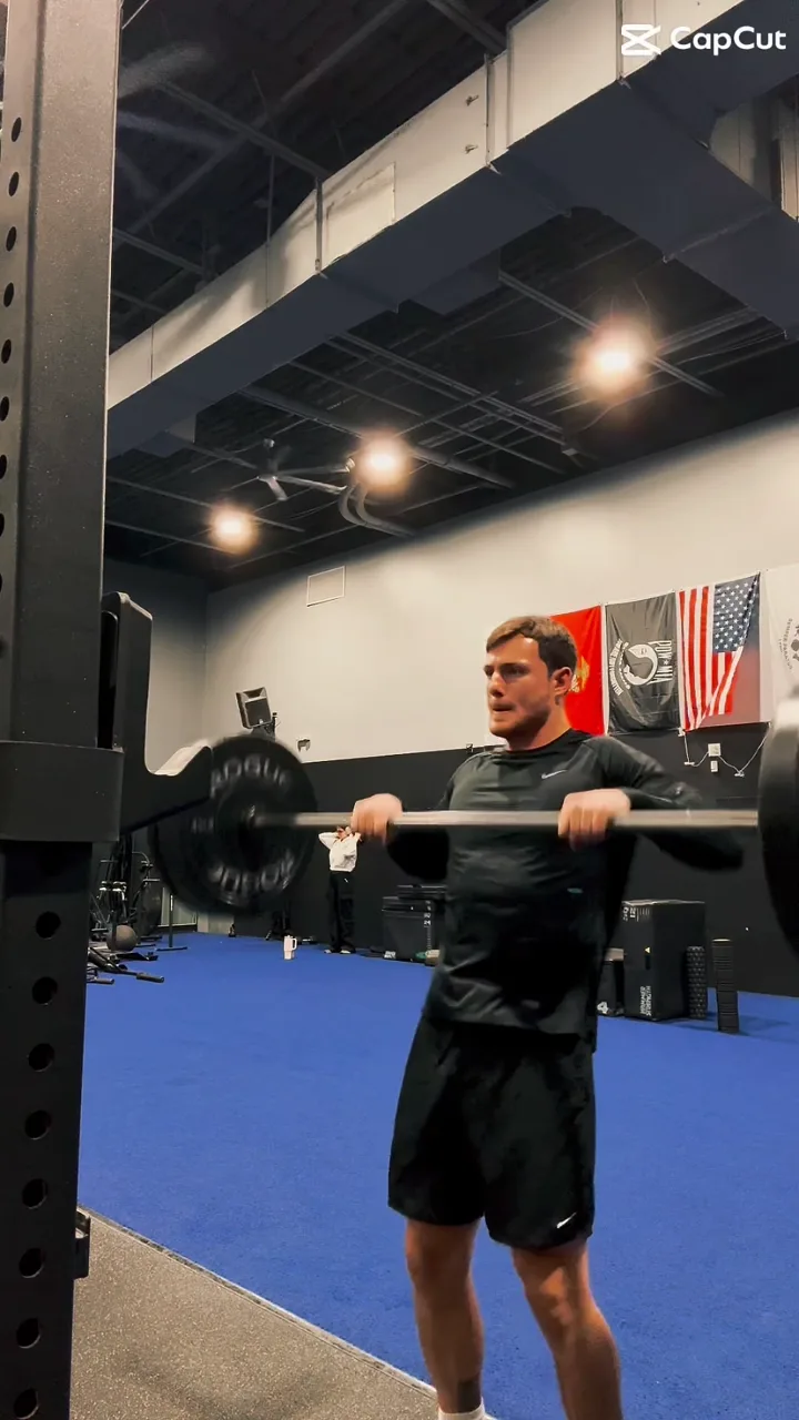 Barbell held in the front-rack position in a strength gym with turf flooring during a 1-on-1 session